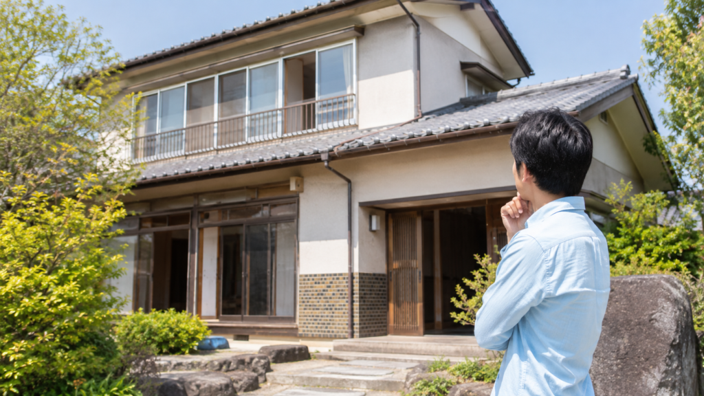 相続した実家の前で売却時期を考える男性の様子